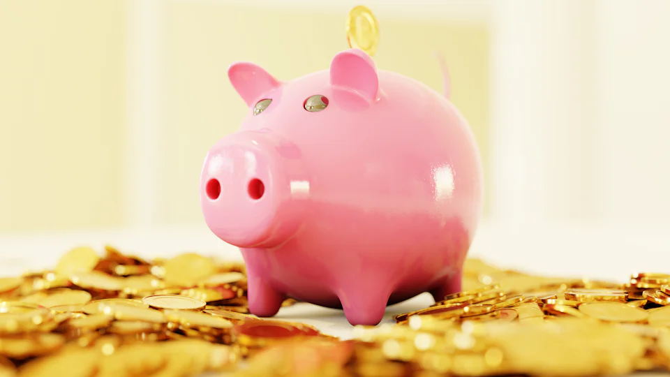 A pink piggy bank on a pile of coins